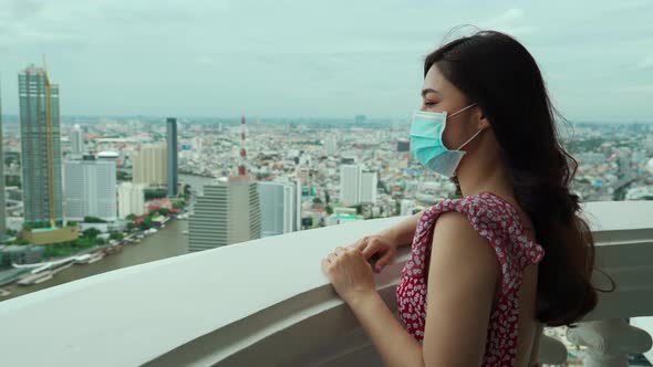 young woman wearing medical mask for prevent to coronavirus(covid-19) and looking view of the city