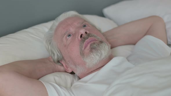 Serious Old Man Laying Awake in Bed 