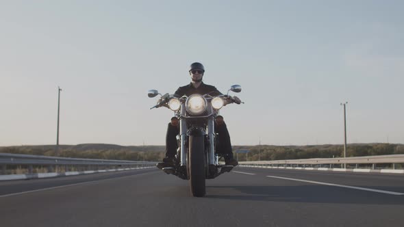 Young caucasian man wearing a hard hat and sunglasses rides a motorcycle.
