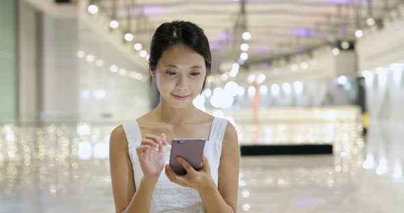 Woman use of cellphone and walking in the shopping mall