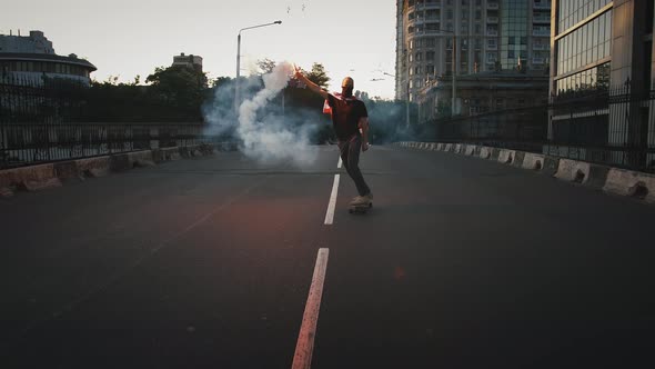 Young Male in Bandana on Face and Flag of USA Tied on Chest is Skateboarding Along Deserted Street