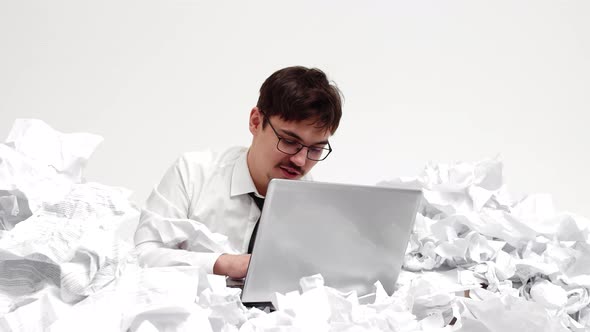 Male Office Worker with Laptop in Hands is Belt in Crumpled Pieces of Paper Front View