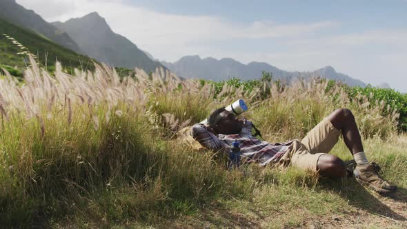 African american man lying on a rock while trekking in the mountains