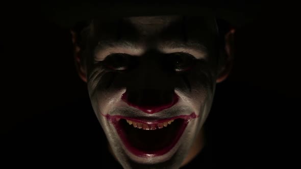 Scary Man in a Clown Makeup Looks at the Camera and Laughs