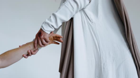 Man's Hand Reaches Out Into the Hands of Jesus on a White Background