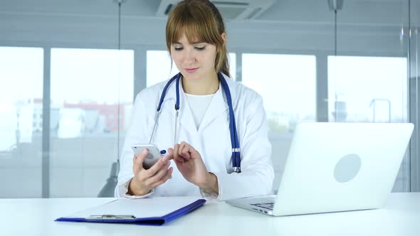 Young Female Doctor Browsing Online on Phone in Hospital