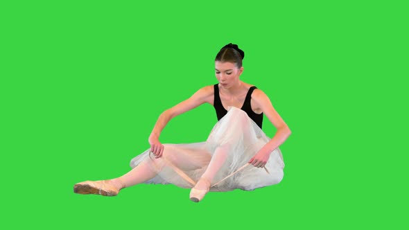 Ballerina Laces Up Pointe with Ballet Ribbons While Sitting on the Floor on a Green Screen Chroma