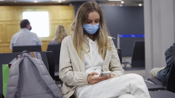 Woman Tourist Wearing Medical Protection Mask Using Mobile Phone in Airport Terminal