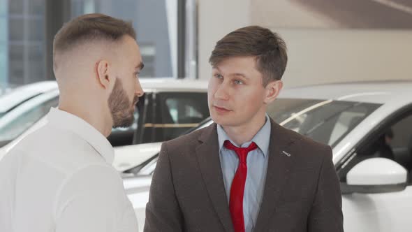 Mature Male Car Dealer Helping His Client Choosing New Auto