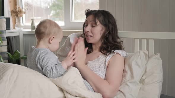 Mother Waking Up with Newborn Playing on Bed