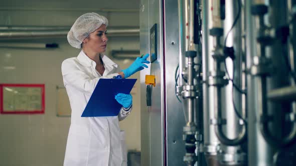 Dairy Plant Worker Writes Notes While Checking Equipment.