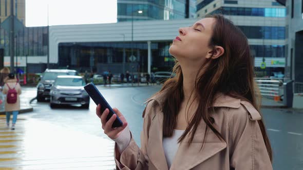 Happy Girl with Cell Phone Stands in Rain