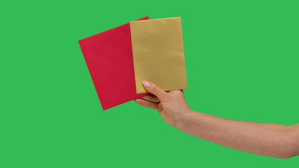 Female Hand Holds Two Paper Envelopes Isolated Closeup on a Green Screen Background Chroma Key in