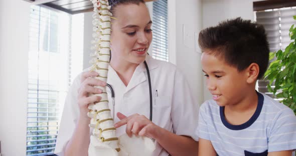 Female physiotherapist explaining spine model to boy patient 4k