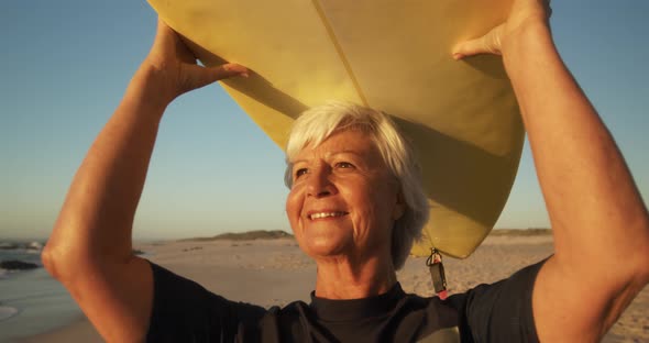 Senior woman with a surfboard smiling