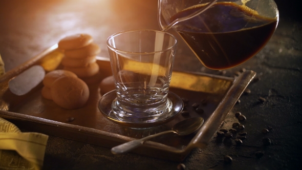 A Glass of Hot Steamy Black Coffee on a Metal Tray, Standing on a Wooden Table, Surrounded By Coffee