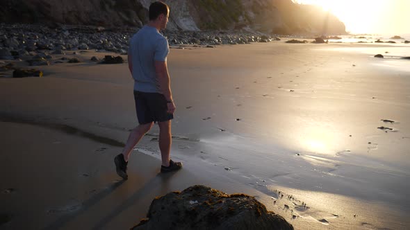 A strong young man walking on the beach after a morning fitness workout at sunrise in Santa Barbara,