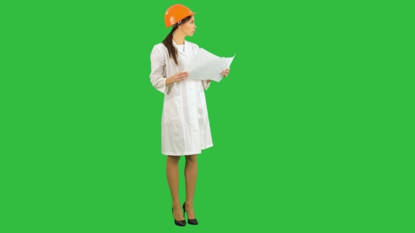 Young Female Architect Holding Blueprints and Inspecting Construction on a Green Screen, Chroma Key alt