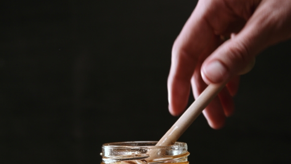 Person Dipping Honey Stick in Honey