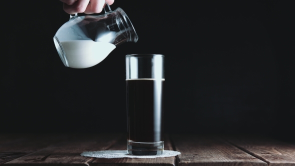 Glass of Coffee Being Mixed with Milk