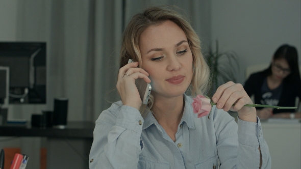 Happy Female Office Worker Talking on the Phone and Holding Rose