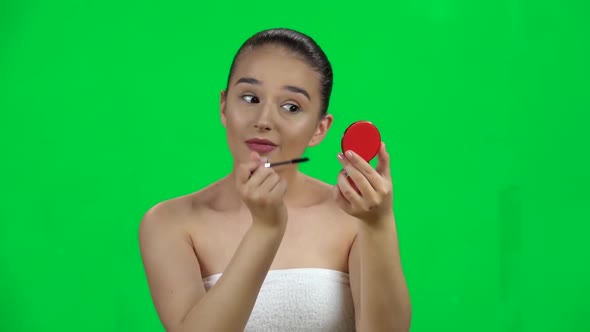Woman Applying Mascara on Eyelashes Looking in a Red Mirror, Green Screen. Slow Motion