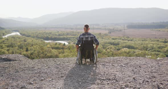 Man with Extraordinary Hairdo Sitting in Wheelchair and Looking at Wonnderful Nature