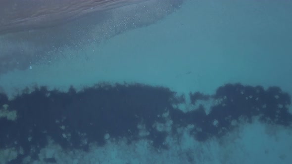 Aerial view of tropical sea waves splashing on the beach.