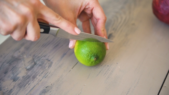 Human Hands Cutting a Slice of Lime in Pieces for Preparing Mojito Cocktail in Kitchen