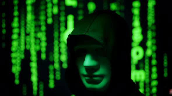 Close Up of a Anonymous Computer Hacker in Black Hood and Mask Over Abstract Binary Matrix