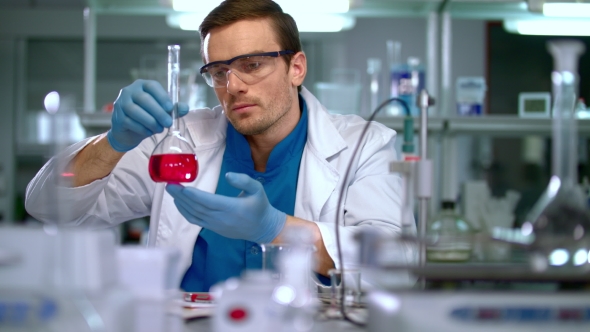 Scientist in Lab. Scientist Looking at Chemical Liquid in Research Laboratory