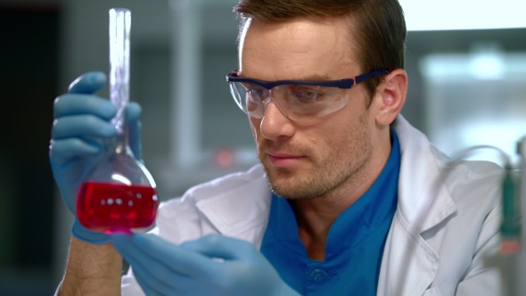 Chemist in Lab.  of Male Chemist Looking at Liquid in Glass Flask alt