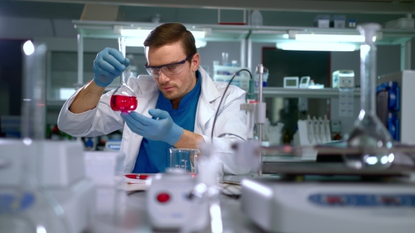 Researcher Analyzing Liquid in Glass Flask and Writing Data at Research Lab