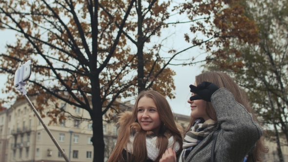 Two Young Girls Friends Do Selfi Autumn in One of the City Streets.