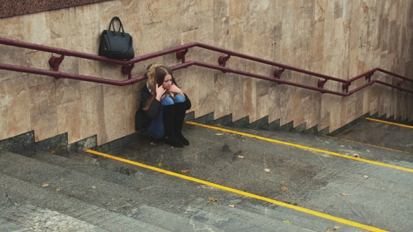 Young Girl on the Stairs in the Subway Depressed Sitting Alone Obscures the Face with His Hands