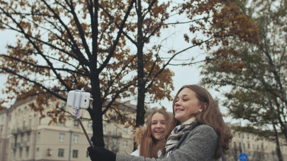 Two Young Girls Friends Do Selfi Autumn in One of the City Streets.