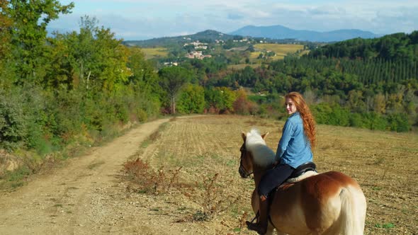 Young woman riding on horse through idyllic landscape