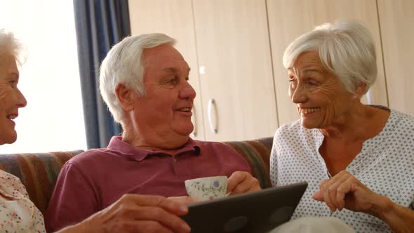 Senior friends discussing together with a digital tablet