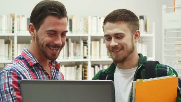 Two Young Students Laugh Standing in Library