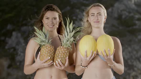 Happy Women with Pineapples and Melons in Bikini on Beach