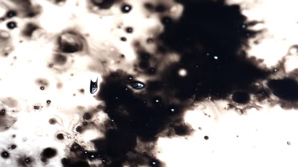 Clip of black ink splashes over white paper