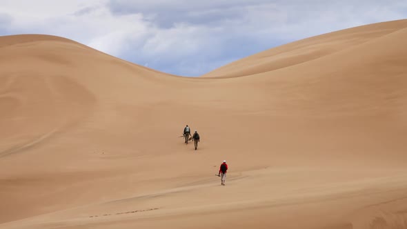 Travelers in Desert Dunes in Mountains