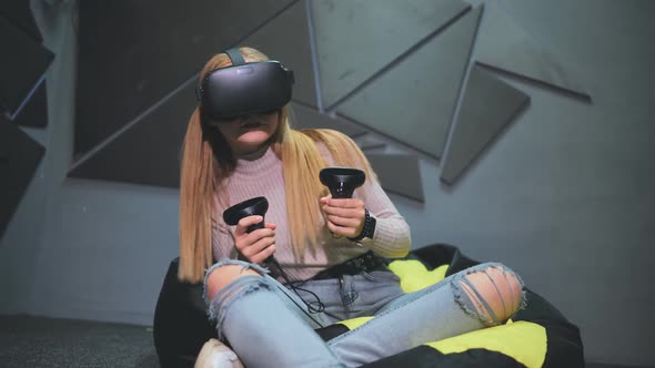 A Teenage Girl Sits in a Club with Virtual Glasses and Plays