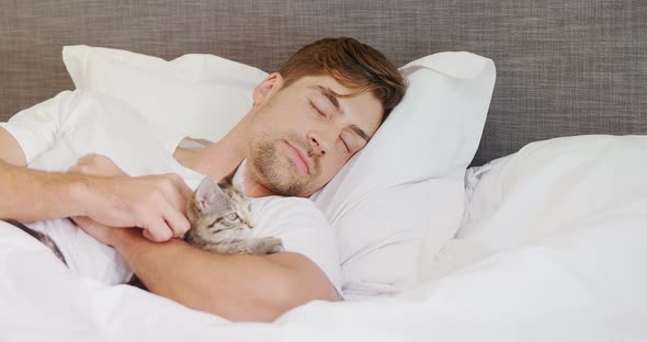 Young man sleeping on bed holding cat in his arms 4K 4k