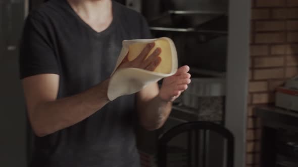 Crop chef stretching and tossing pizza dough