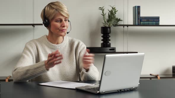 Smiling Middleaged Modern Woman Wears a Headset a Distance Course or Training on a Laptop