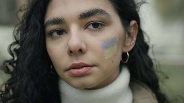 Close up portrait of young woman with Ukrainian flag painted on her cheek. Shot with RED helium came