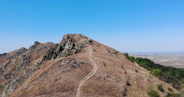 Rugged Mountain With Hiking Trail Against Sunny Blue Sky In Romania. Macin Mountains