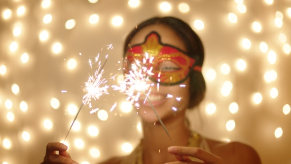 Merry Young Woman in Mask with Sparklers on Christmas Eve
