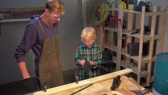 Boy Puts on Protective Gloves in the Workshop